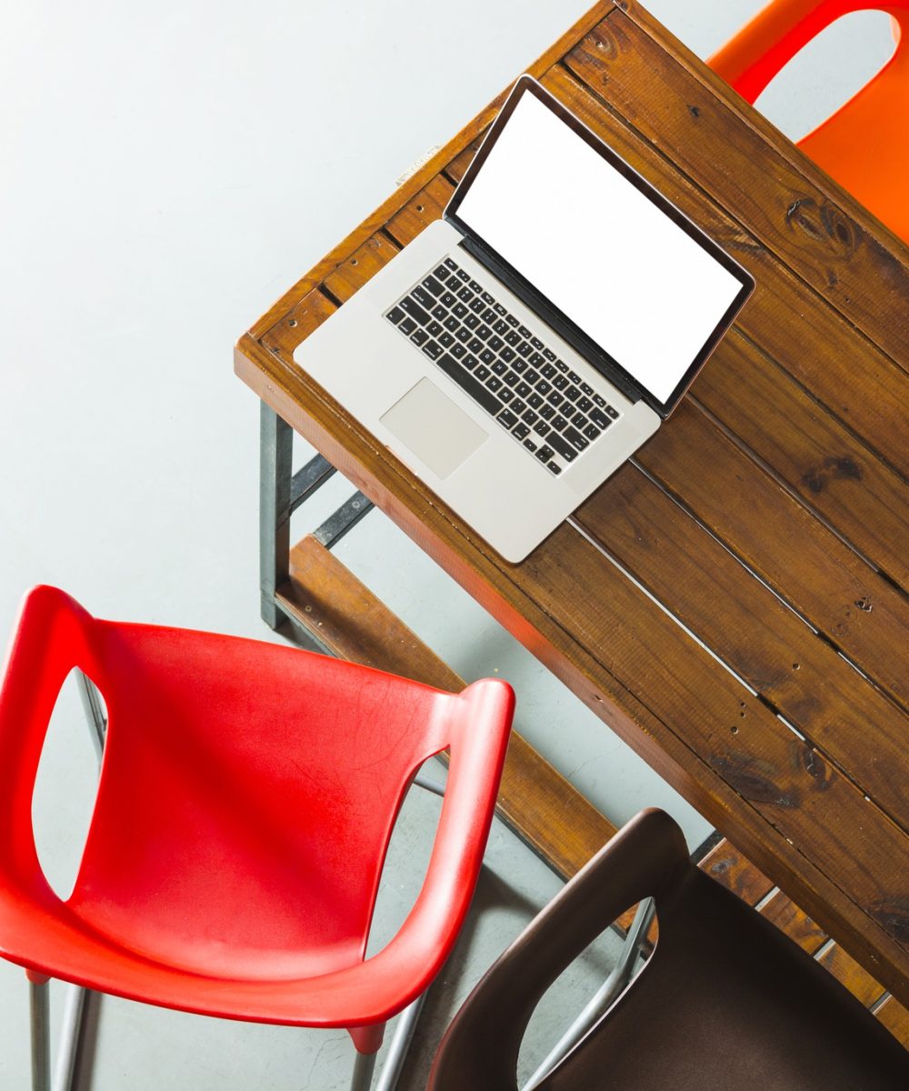 overhead-view-open-laptop-wooden-table-with-colorful-chairs overhead-view-open-laptop-wooden-table-with-colorful-chairs